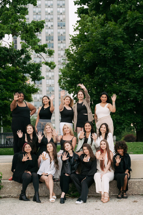 A diverse team of women waving to the camera