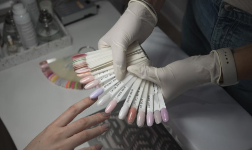 Gloved hands showing The GelBottle Inc builder gel color swatches